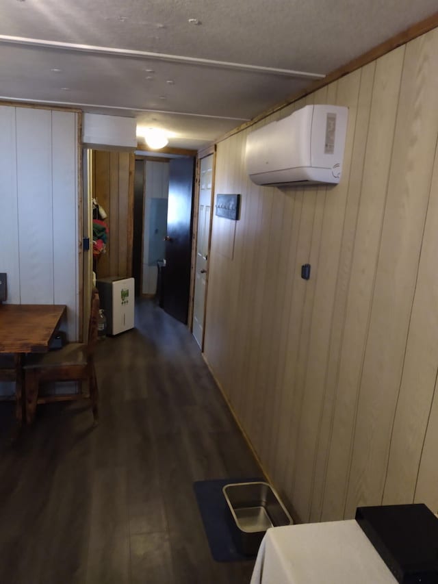 corridor with a wall mounted AC and dark hardwood / wood-style flooring