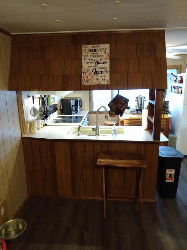 kitchen featuring range with electric stovetop, dark wood-type flooring, wooden walls, and kitchen peninsula