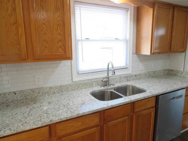 kitchen featuring sink, backsplash, stainless steel dishwasher, and light stone countertops