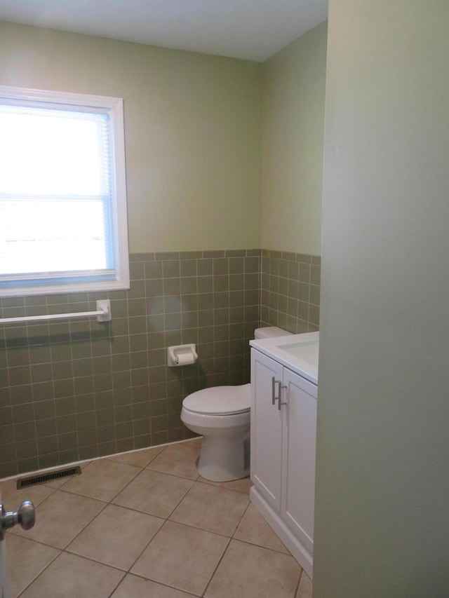 bathroom featuring tile patterned flooring, vanity, tile walls, and toilet