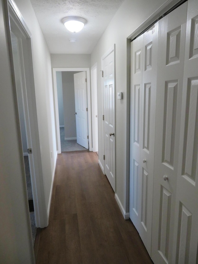 hallway featuring dark hardwood / wood-style floors and a textured ceiling