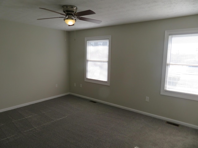 carpeted empty room with ceiling fan and plenty of natural light