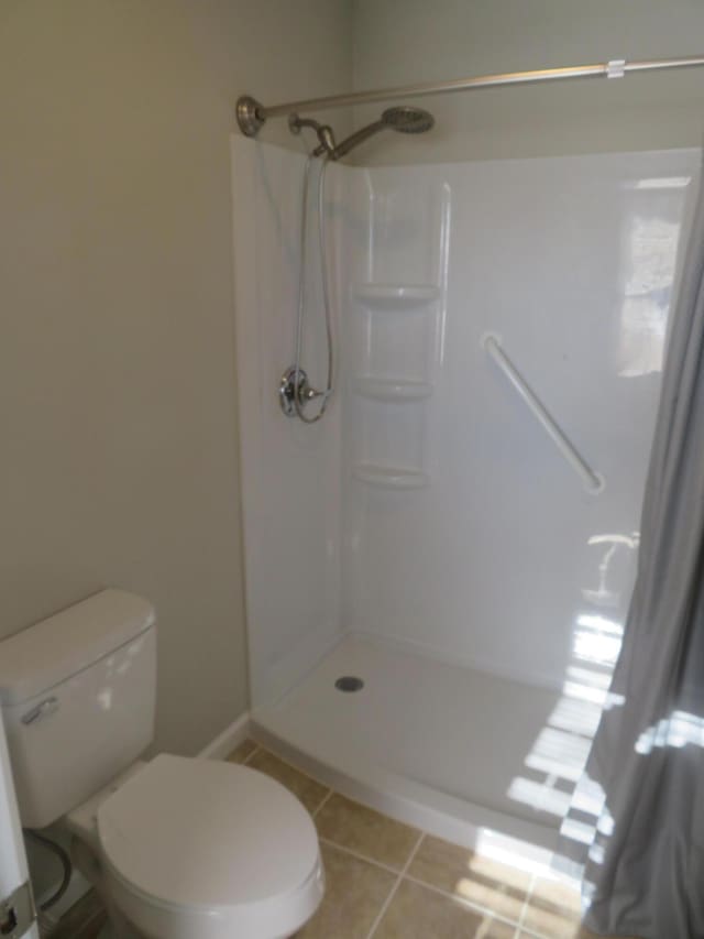 bathroom featuring tile patterned floors, toilet, and a shower