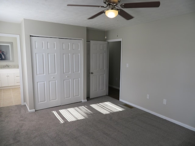 unfurnished bedroom with connected bathroom, sink, carpet floors, a closet, and ceiling fan