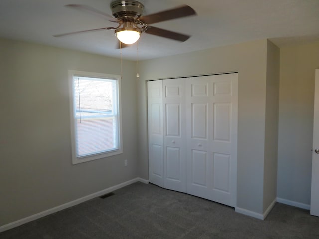 unfurnished bedroom featuring ceiling fan, a closet, and dark colored carpet