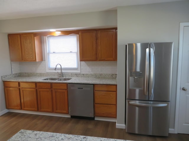 kitchen with dark hardwood / wood-style floors, sink, backsplash, stainless steel appliances, and light stone countertops