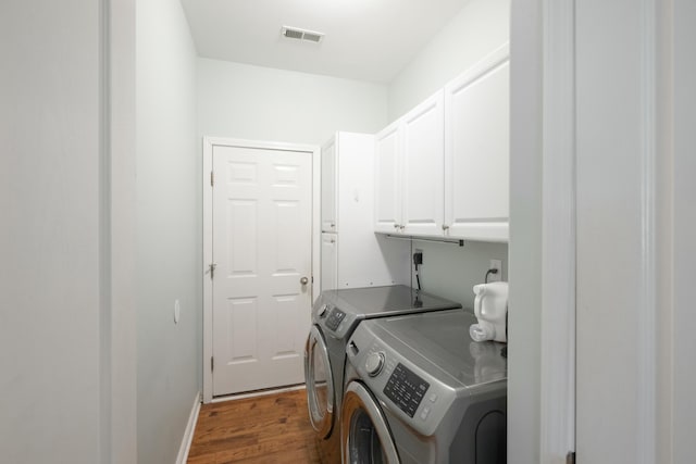 laundry area with cabinets, dark hardwood / wood-style flooring, and washing machine and dryer