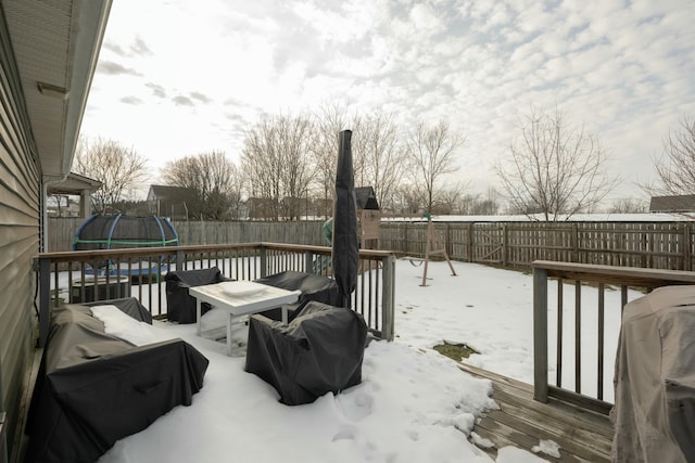 snow covered deck with a trampoline and a grill