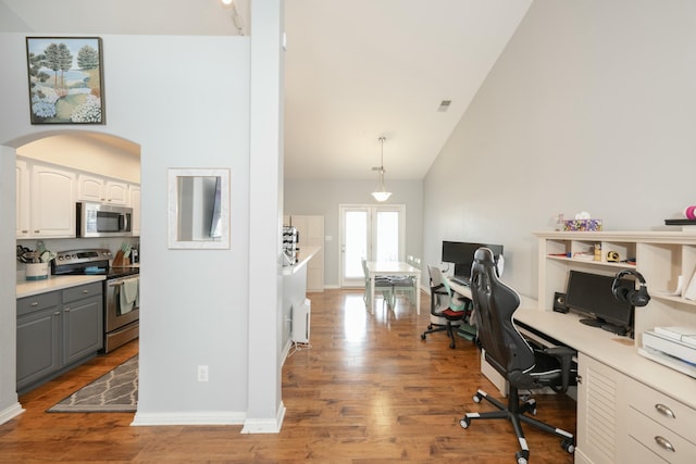 home office with high vaulted ceiling and light hardwood / wood-style floors