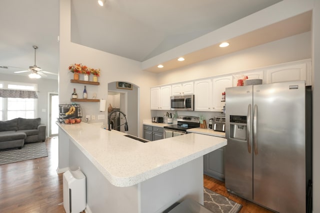 kitchen featuring lofted ceiling, sink, white cabinetry, appliances with stainless steel finishes, and kitchen peninsula