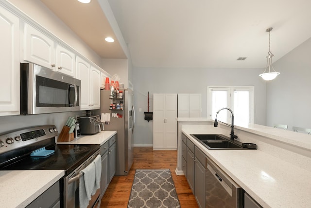 kitchen with stainless steel appliances, white cabinetry, hanging light fixtures, and sink