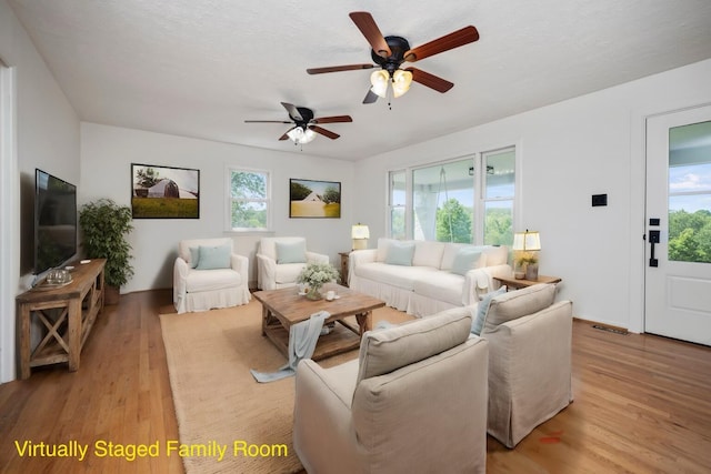 living room with ceiling fan, a textured ceiling, and light hardwood / wood-style flooring