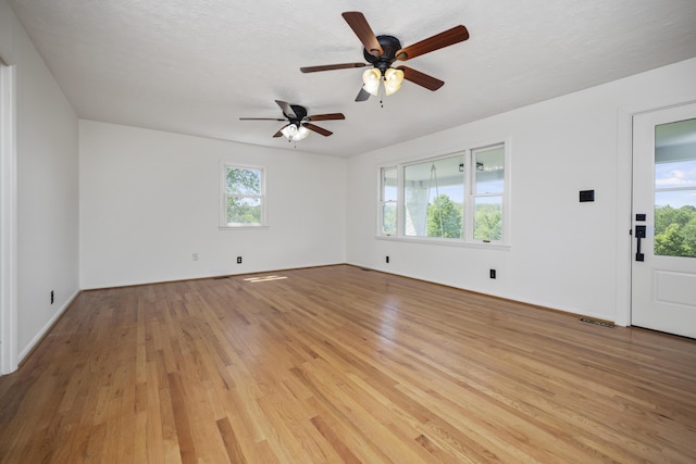 empty room with ceiling fan, a textured ceiling, and light hardwood / wood-style floors