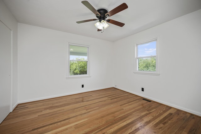 empty room with hardwood / wood-style flooring, plenty of natural light, and ceiling fan