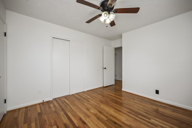 unfurnished bedroom featuring hardwood / wood-style flooring, a textured ceiling, ceiling fan, and a closet