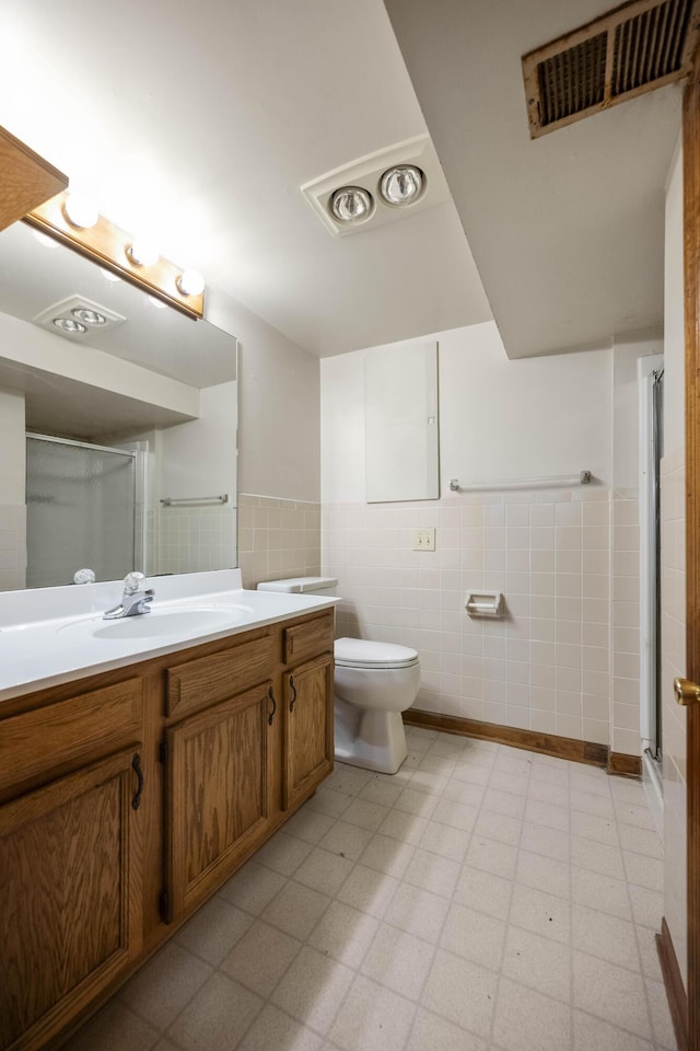 bathroom featuring a shower with door, vanity, tile walls, and toilet