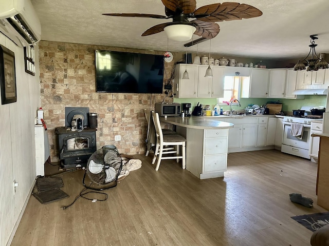 kitchen featuring white cabinetry, white range with gas cooktop, a wall mounted AC, and a kitchen breakfast bar