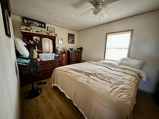 bedroom with ceiling fan, a textured ceiling, and dark hardwood / wood-style flooring