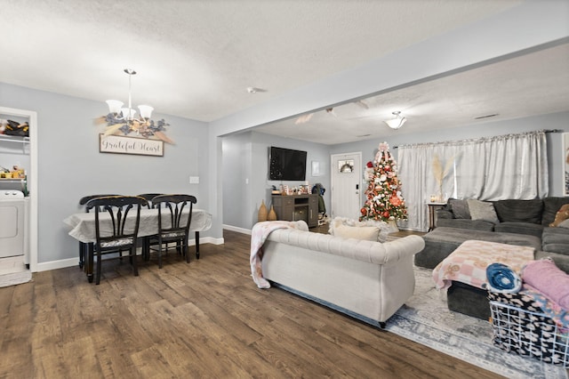 living room featuring dark hardwood / wood-style flooring, a notable chandelier, washer / dryer, and a textured ceiling