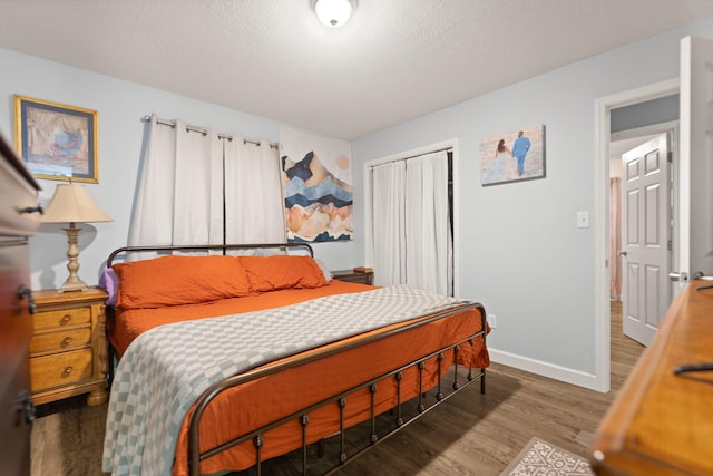 bedroom featuring dark wood-type flooring, a textured ceiling, and a closet