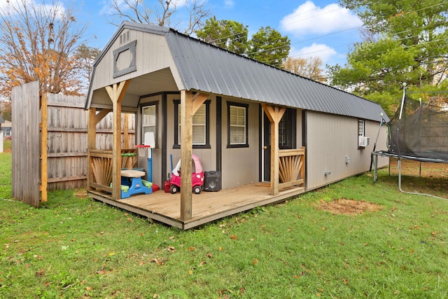 view of outbuilding featuring a trampoline and a lawn