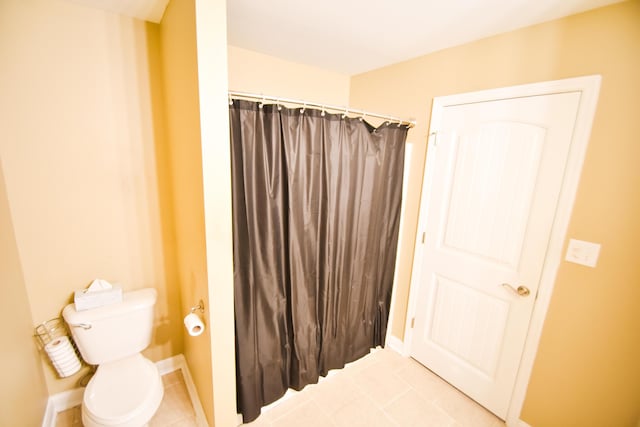 bathroom featuring tile patterned flooring, toilet, and walk in shower