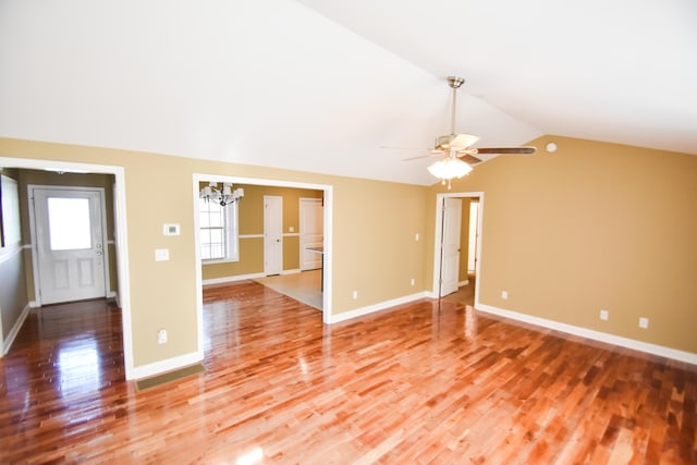 unfurnished living room with ceiling fan with notable chandelier, vaulted ceiling, and wood-type flooring