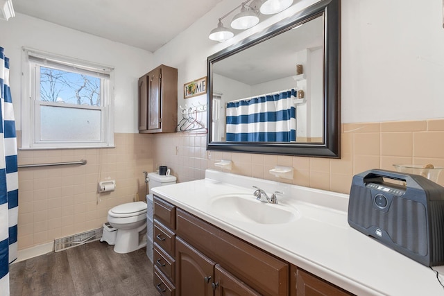 bathroom with hardwood / wood-style flooring, vanity, tile walls, and toilet