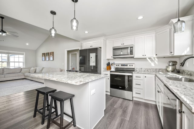 kitchen with vaulted ceiling, a kitchen island, white cabinetry, sink, and stainless steel appliances