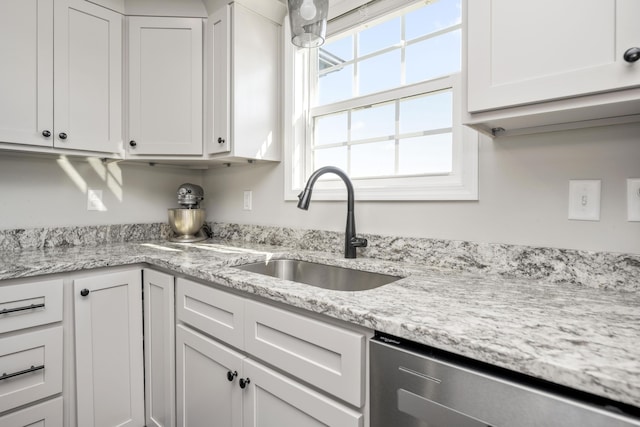 kitchen with sink, stainless steel dishwasher, white cabinets, and light stone counters