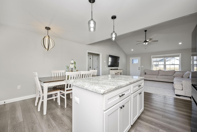 kitchen featuring a kitchen island, white cabinets, hanging light fixtures, light stone countertops, and light hardwood / wood-style flooring