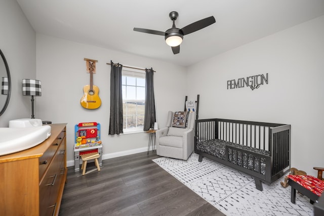 bedroom with sink, dark wood-type flooring, a nursery area, and ceiling fan