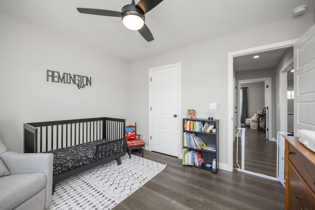 bedroom with ceiling fan, dark hardwood / wood-style flooring, and a crib