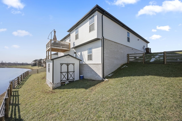 exterior space featuring a lawn, a storage unit, and a water view