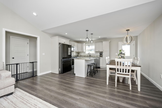 interior space with white cabinetry, hanging light fixtures, a kitchen breakfast bar, stainless steel appliances, and a center island