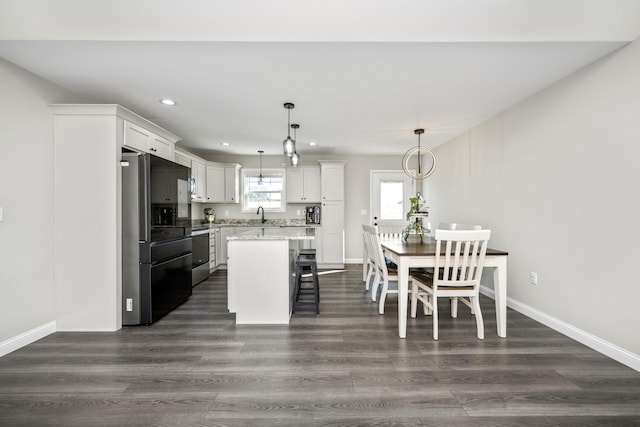 kitchen with a kitchen island, dark hardwood / wood-style floors, decorative light fixtures, white cabinets, and stainless steel appliances