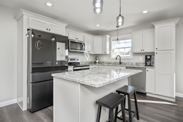 kitchen with dark hardwood / wood-style flooring, a center island, white cabinets, and appliances with stainless steel finishes