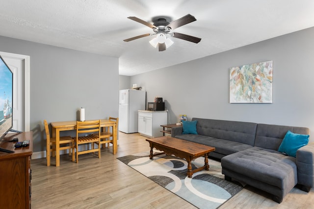 living room with a textured ceiling, light hardwood / wood-style flooring, and ceiling fan