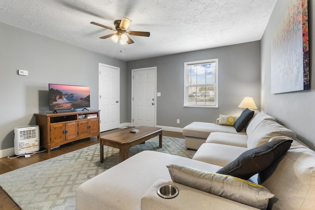 living room featuring ceiling fan, dark hardwood / wood-style floors, and a textured ceiling