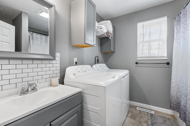 clothes washing area featuring sink, cabinets, washer and dryer, and a textured ceiling