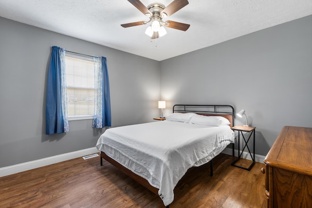 bedroom with dark hardwood / wood-style flooring, a textured ceiling, and ceiling fan