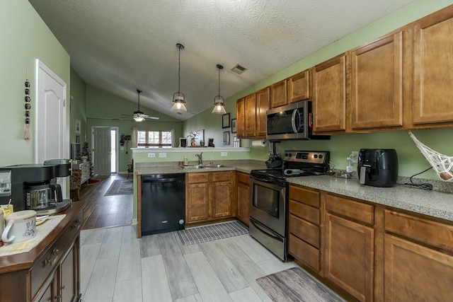 kitchen featuring pendant lighting, lofted ceiling, sink, kitchen peninsula, and stainless steel appliances