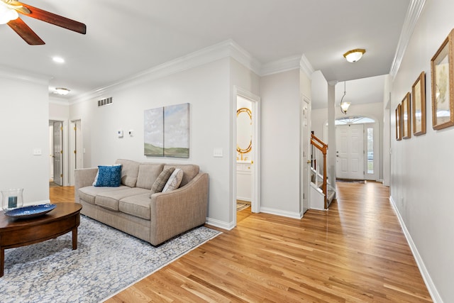 living room with crown molding, ceiling fan, and light hardwood / wood-style flooring