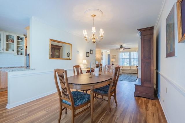 dining space featuring crown molding, ceiling fan with notable chandelier, and light hardwood / wood-style floors