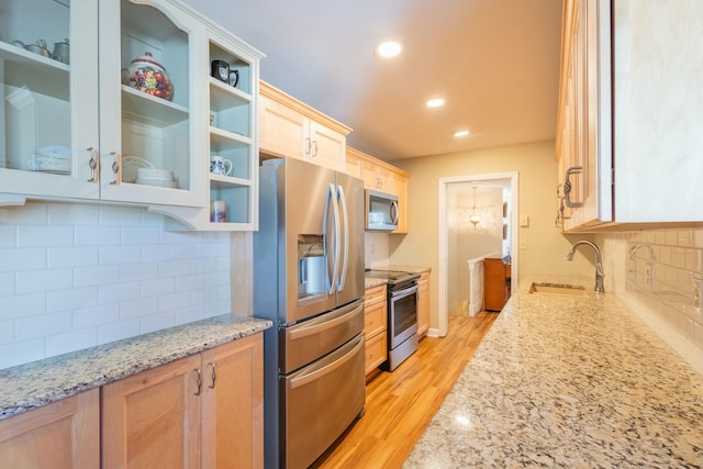 kitchen featuring stainless steel appliances, light stone countertops, sink, and light brown cabinets