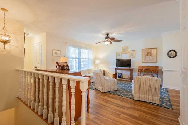 living room featuring crown molding, wood-type flooring, and ceiling fan with notable chandelier