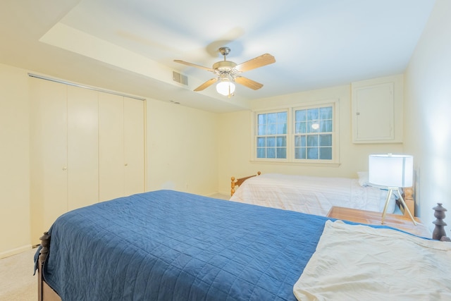 bedroom with ceiling fan, light colored carpet, and a closet