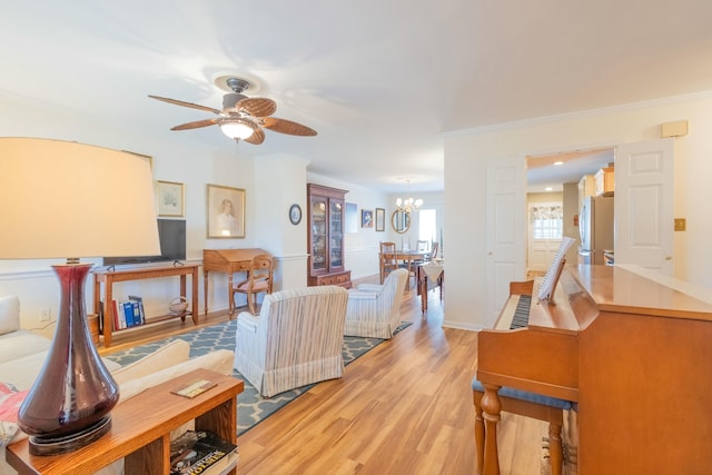 living room featuring crown molding, ceiling fan with notable chandelier, and light hardwood / wood-style floors