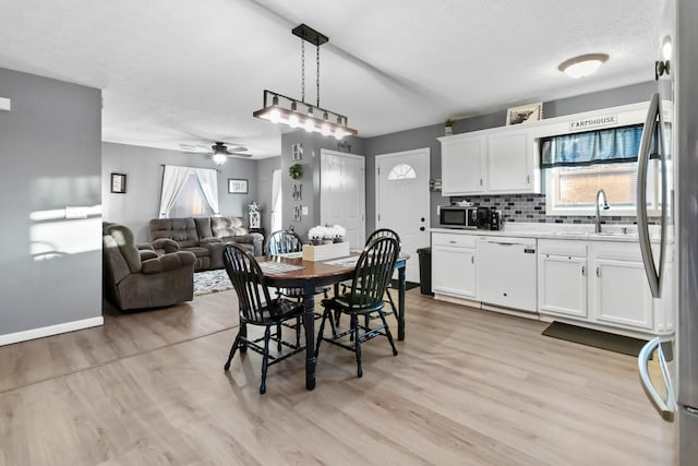 dining space with ceiling fan, light hardwood / wood-style floors, sink, and a textured ceiling