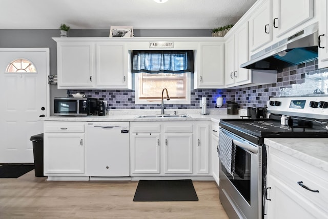 kitchen with sink, light hardwood / wood-style flooring, appliances with stainless steel finishes, white cabinetry, and tasteful backsplash